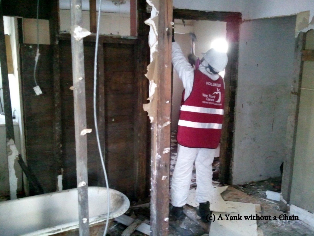 A New York Cares volunteer pulling down moldy walls