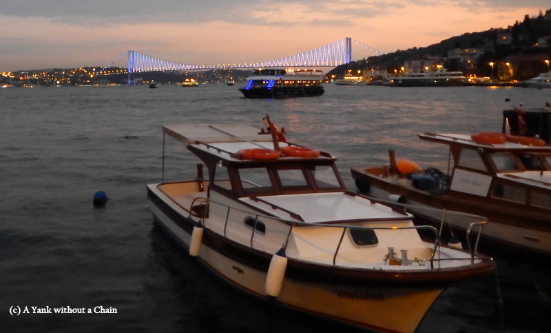 Some boats with the lit up Bosphorus Bridge in the background