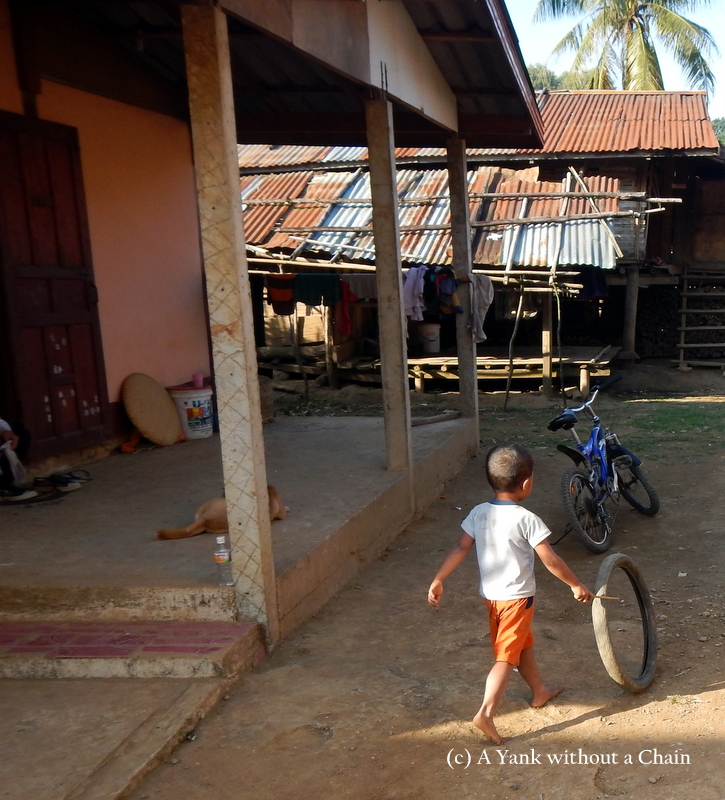 A young boy playing with a tire at Ban Houay Thong Village
