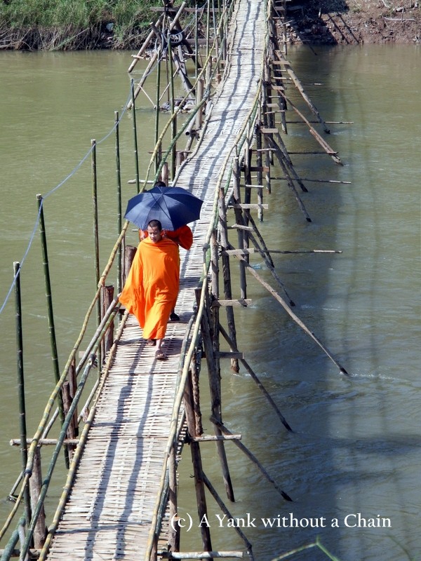 Monks walking across a bamboo bridge in Luang Prabang
