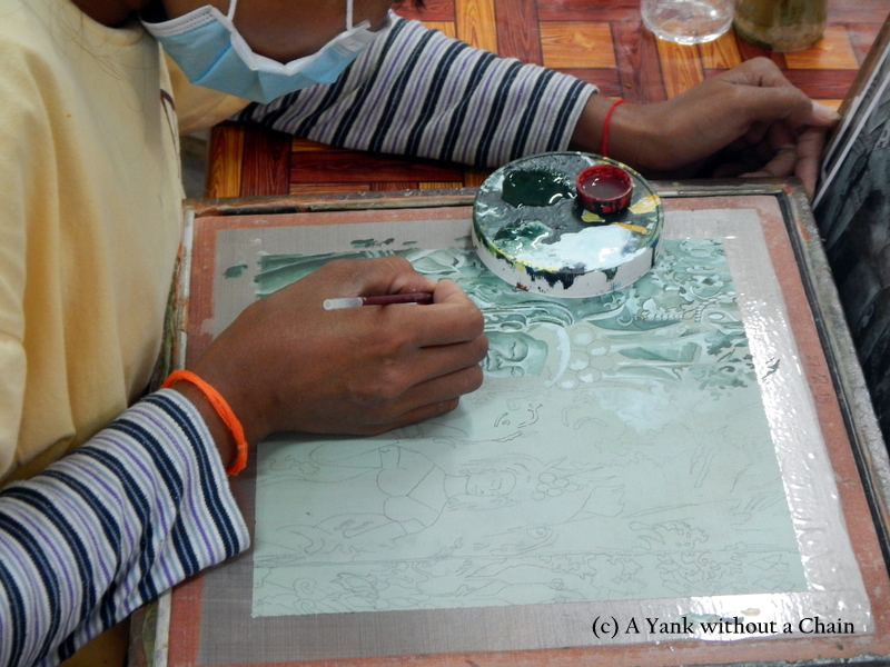 A woman painting a piece at the Artisans Angkor workshop