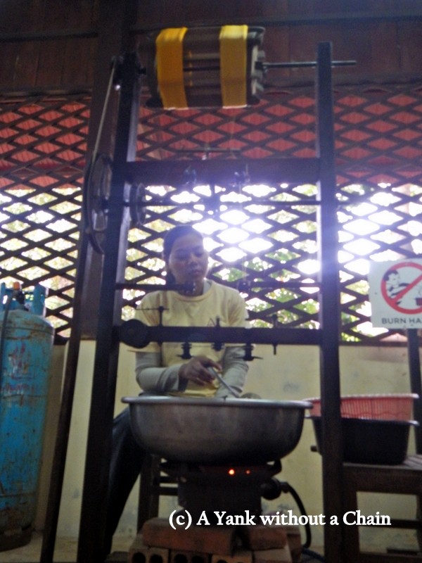 A woman uses boiling water to separate out silk strands from the worms' cocoons