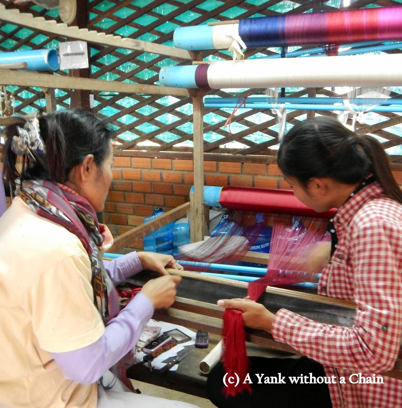 Women demonstrating how a weaving frame is set up at the silk farm